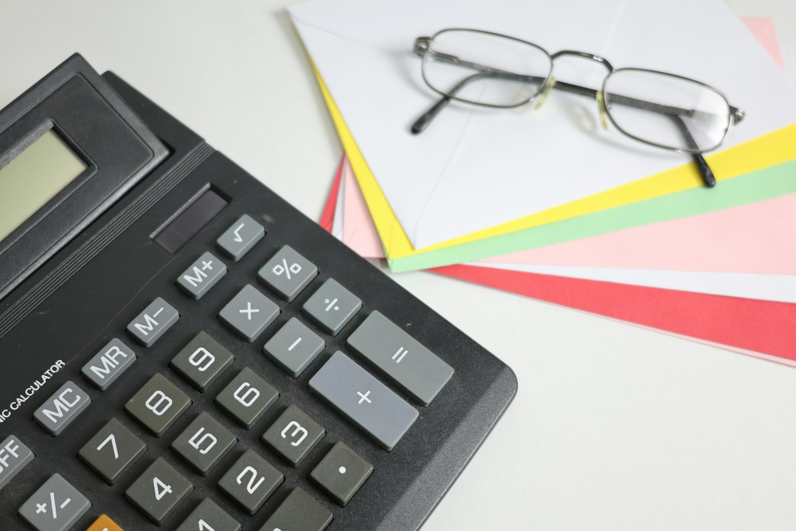 Calculator and glasses on colorful financial papers
